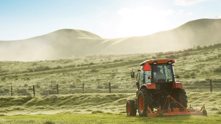 kioti tractor in a field, mowing the pasture